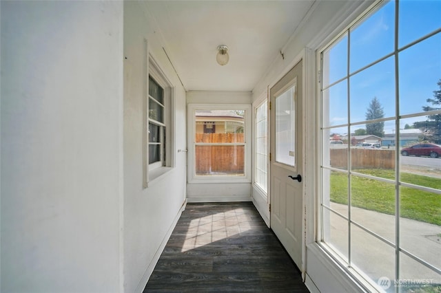 unfurnished sunroom featuring baseboards and wood finished floors