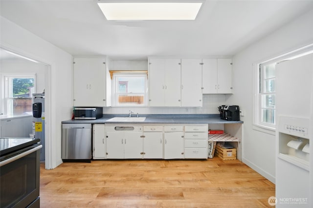 kitchen with a sink, light wood finished floors, appliances with stainless steel finishes, and white cabinets