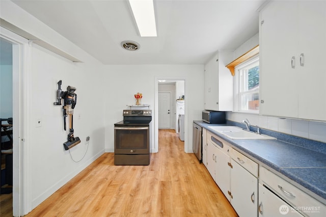 kitchen with a sink, light wood finished floors, appliances with stainless steel finishes, and white cabinets