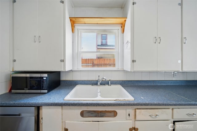 kitchen with stainless steel appliances, dark countertops, and a sink