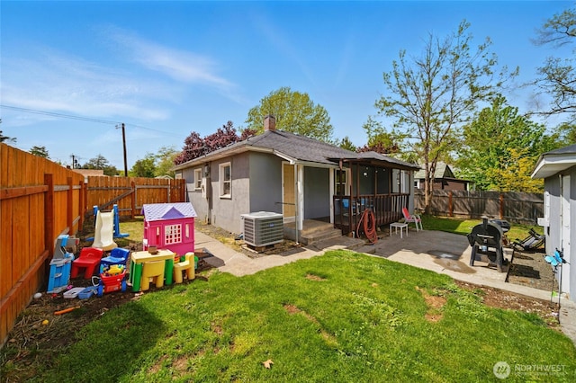 rear view of house with a lawn, a patio, central AC, and a fenced backyard