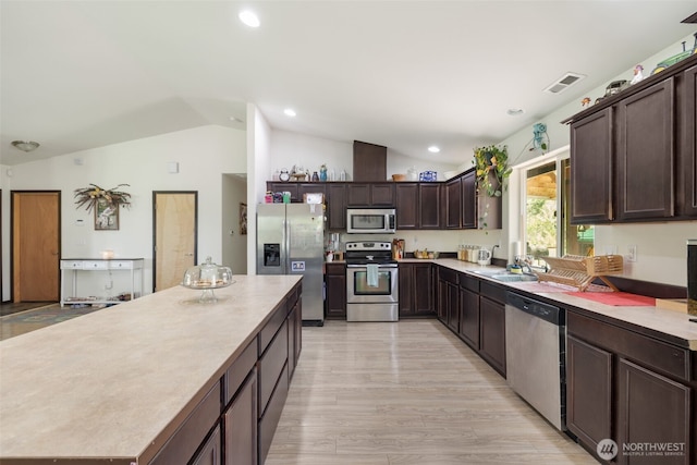 29304 39th Ave E, Graham, WA 98338 - kitchen with visible vents, a center island, vaulted ceiling, dark brown cabinets, and stainless steel appliances