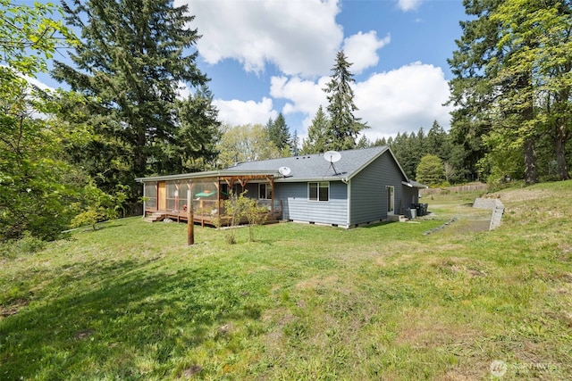 29304 39th Ave E, Graham, WA 98338 - back of property featuring a lawn, a deck, a shingled roof, and a sunroom