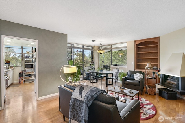 living area featuring a textured ceiling, built in features, and light wood-style floors
