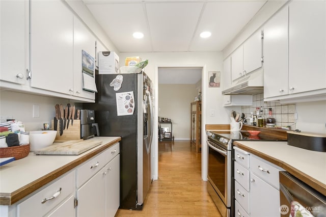 kitchen featuring under cabinet range hood, white cabinets, light wood finished floors, backsplash, and stainless steel appliances