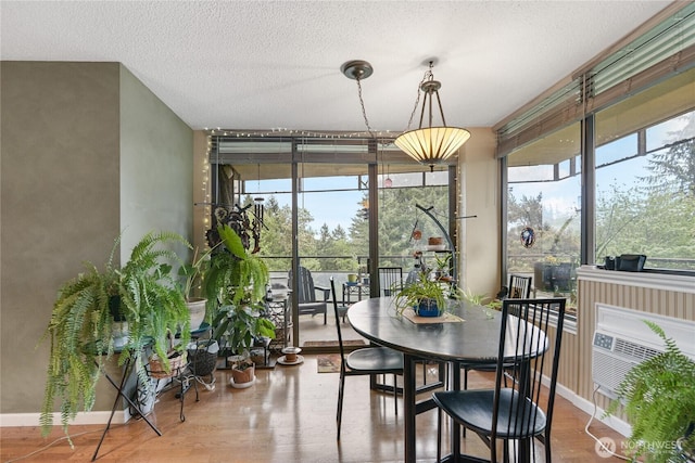 dining area featuring baseboards, a textured ceiling, wood finished floors, and a wealth of natural light