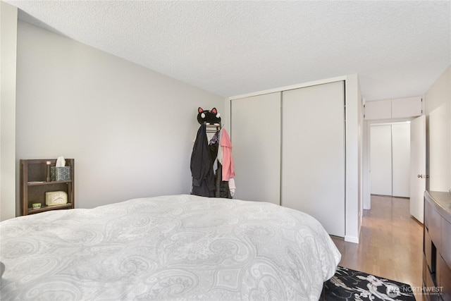 bedroom with wood finished floors and a closet
