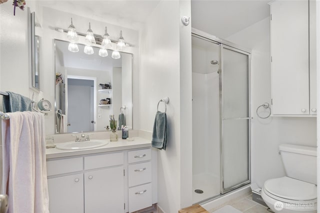 bathroom featuring toilet, a shower stall, and vanity