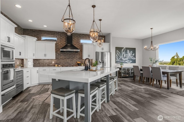 1614 W 51st Ave, Kennewick, WA 99337 - kitchen with a chandelier, wine cooler, a warming drawer, stainless steel appliances, and wall chimney exhaust hood