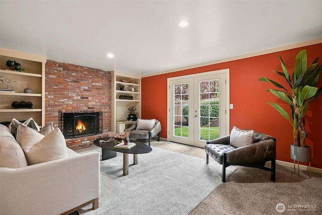 living room featuring french doors, built in features, a brick fireplace, baseboards, and carpet