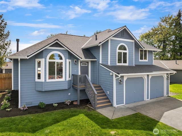 tri-level home with a front lawn, fence, a shingled roof, an attached garage, and driveway