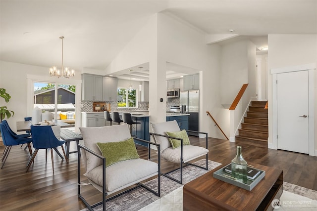 living room with dark wood-type flooring, lofted ceiling, a chandelier, and stairway