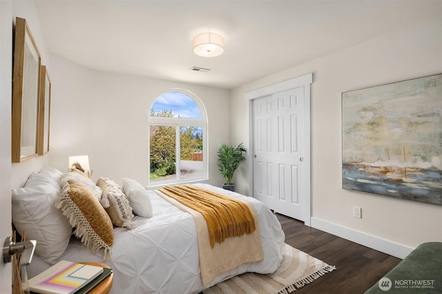 bedroom with baseboards, wood finished floors, and visible vents
