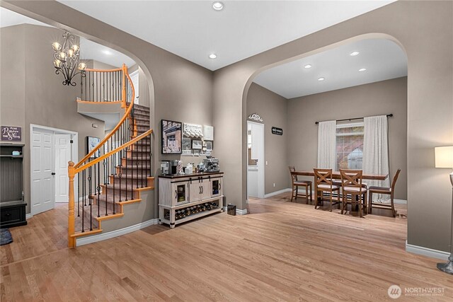 entryway with arched walkways, baseboards, wood finished floors, and stairway