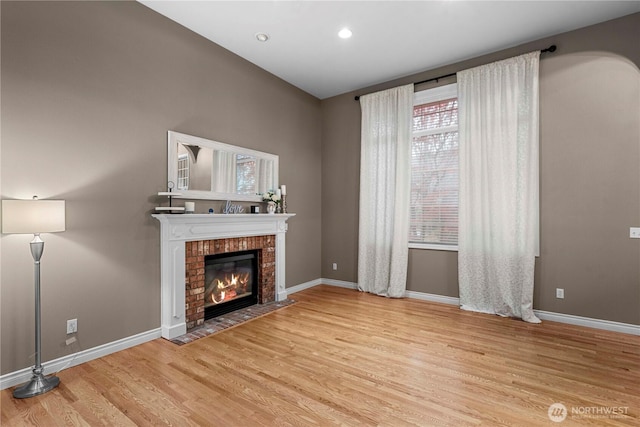 unfurnished living room with a brick fireplace, recessed lighting, baseboards, and wood finished floors