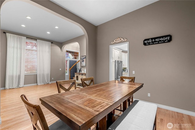 dining room featuring baseboards, arched walkways, light wood-style floors, and recessed lighting