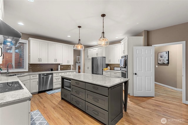 kitchen featuring gray cabinets, appliances with stainless steel finishes, a center island, a sink, and white cabinetry