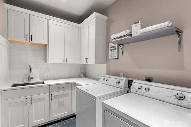 laundry room featuring cabinet space, separate washer and dryer, and a sink