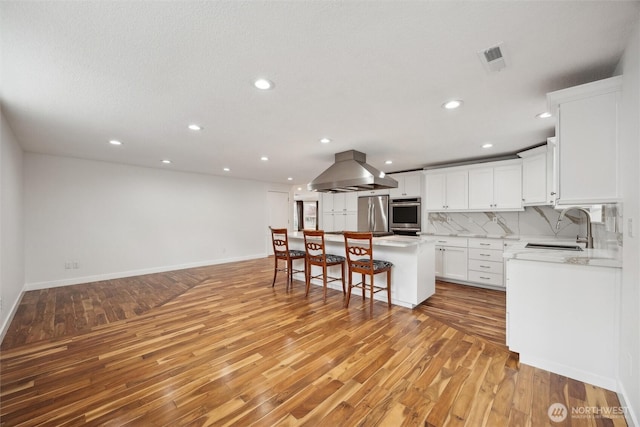 18 SE 18th St, Battle Ground, WA 98604 - kitchen featuring a sink, island exhaust hood, a kitchen breakfast bar, light wood-type flooring, and recessed lighting