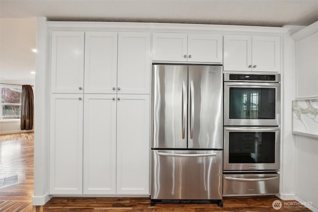 18 SE 18th St, Battle Ground, WA 98604 - kitchen with stainless steel appliances, a warming drawer, white cabinets, and dark wood-style flooring