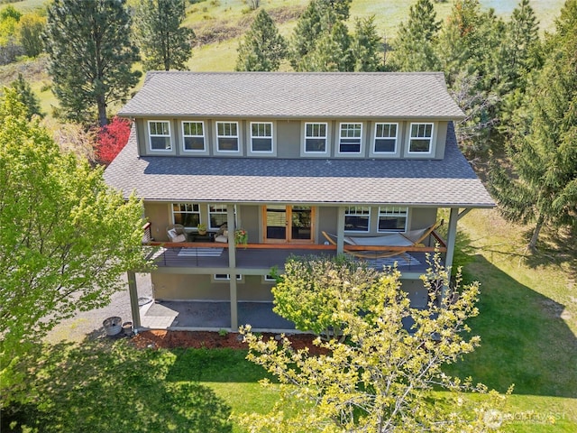 view of front of house featuring a shingled roof, a patio area, and a front yard
