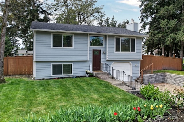 bi-level home featuring fence, a chimney, an attached garage, and a front yard