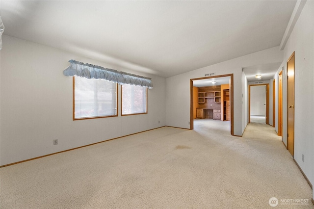 unfurnished room featuring baseboards, visible vents, lofted ceiling, and light colored carpet