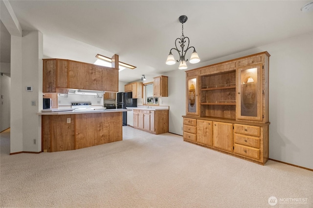 kitchen featuring exhaust hood, freestanding refrigerator, a peninsula, an inviting chandelier, and light carpet
