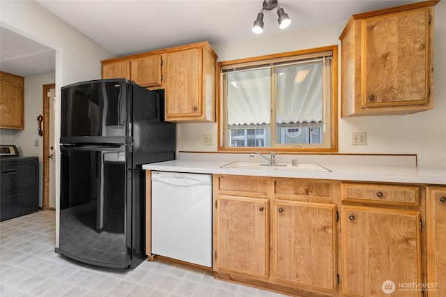 kitchen with white dishwasher, light countertops, a sink, freestanding refrigerator, and washer / dryer