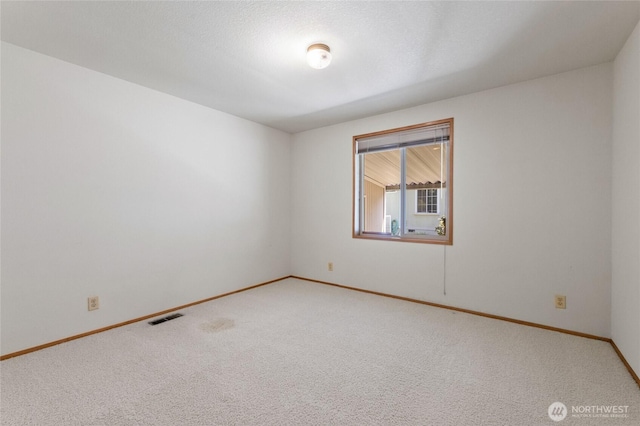 carpeted spare room with visible vents and baseboards
