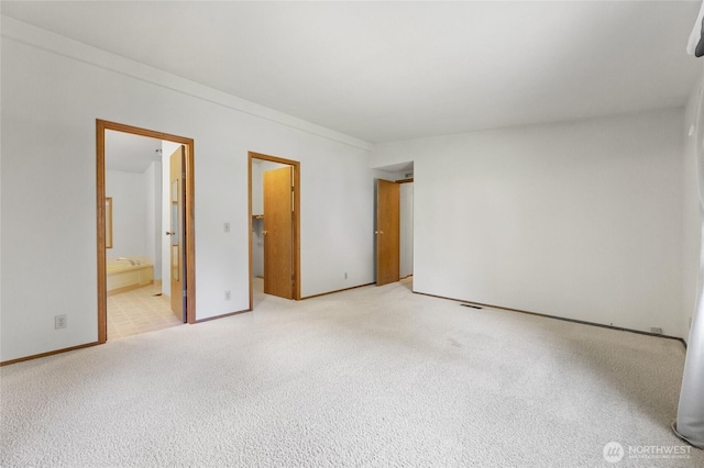 unfurnished bedroom featuring baseboards, connected bathroom, and light colored carpet