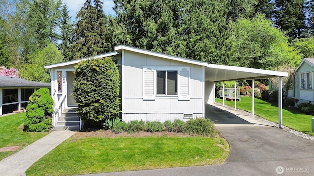 manufactured / mobile home featuring an attached carport, aphalt driveway, crawl space, and a front yard