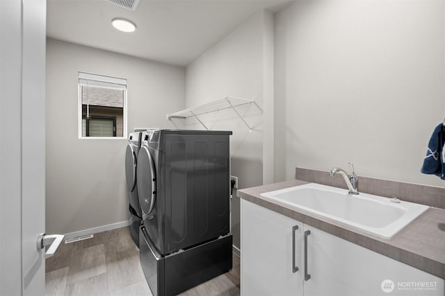 33455 Holly Ave SE, Black Diamond, WA 98010 - clothes washing area featuring washer and dryer, cabinet space, a sink, baseboards, and wood finished floors