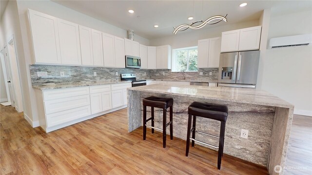 15941 Glenwood Rd SW, Port Orchard, WA 98367 - kitchen with decorative backsplash, a breakfast bar, a wall mounted air conditioner, white cabinets, and stainless steel appliances