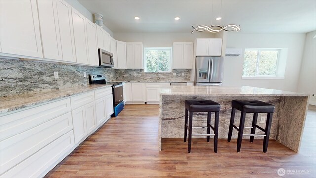 15941 Glenwood Rd SW, Port Orchard, WA 98367 - kitchen featuring backsplash, a kitchen bar, light wood-type flooring, stainless steel appliances, and white cabinetry