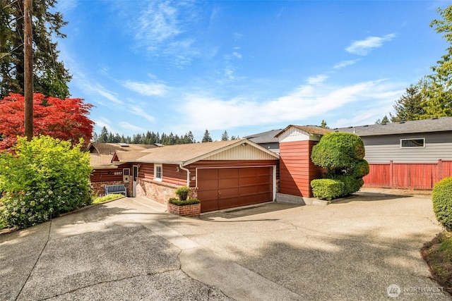 ranch-style home with an attached garage, fence, driveway, and stone siding