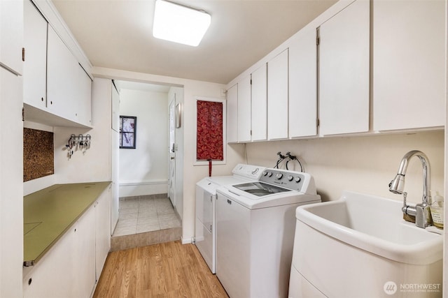 laundry room with a sink, cabinet space, light wood finished floors, and washing machine and clothes dryer