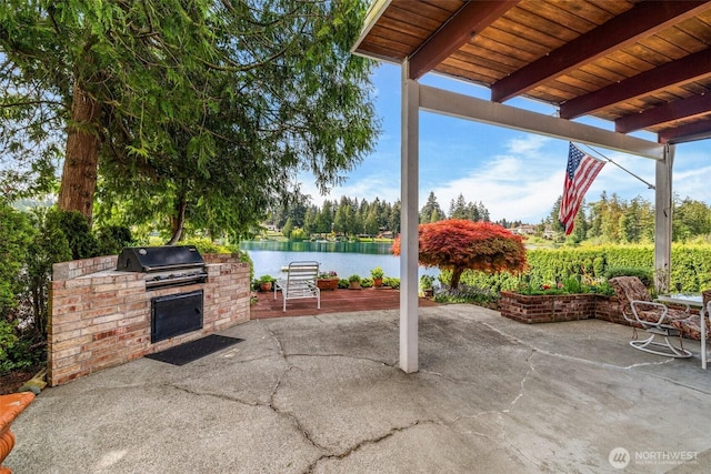 view of patio featuring exterior kitchen, a water view, and a grill