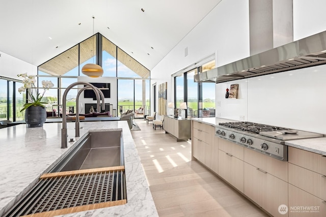 1721 J B George Rd, Walla Walla, WA 99362 - kitchen with wall chimney exhaust hood, high vaulted ceiling, stainless steel gas stovetop, light stone counters, and open floor plan