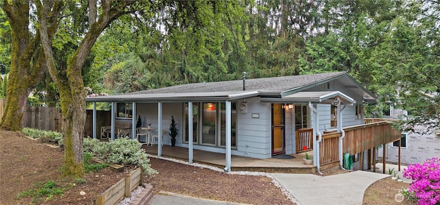 ranch-style home featuring a porch, roof with shingles, and fence