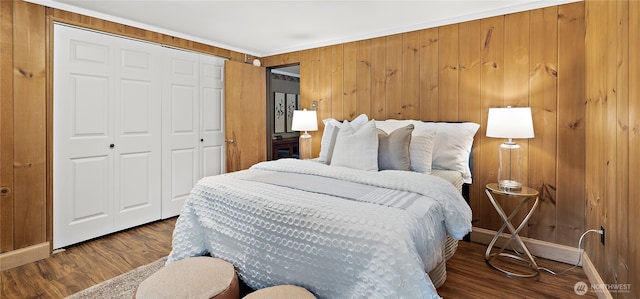 bedroom with baseboards, wood walls, wood finished floors, and a closet