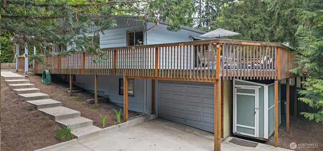 rear view of property with a garage, a wooden deck, and concrete driveway