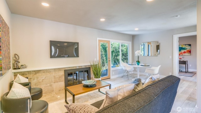 living area featuring baseboards, recessed lighting, wood finished floors, and a tile fireplace