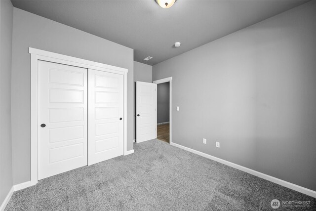 unfurnished bedroom featuring baseboards, carpet flooring, and a closet