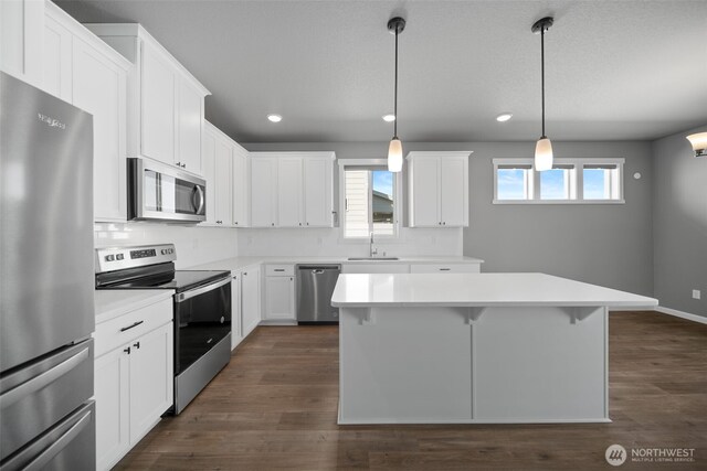 kitchen with a center island, a sink, light countertops, stainless steel appliances, and recessed lighting