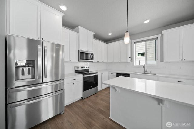 kitchen with dark wood-type flooring, light countertops, white cabinetry, a sink, and stainless steel appliances