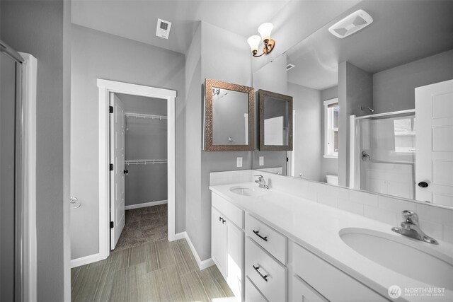 full bathroom with double vanity, visible vents, a shower stall, and a sink