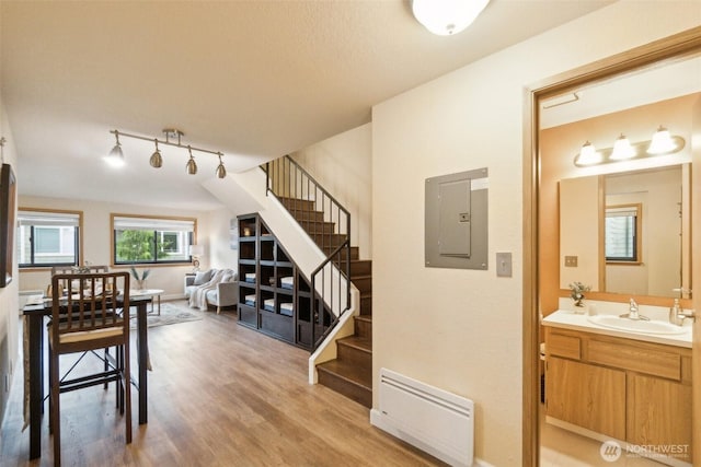 interior space featuring track lighting, electric panel, stairs, and light wood-style flooring