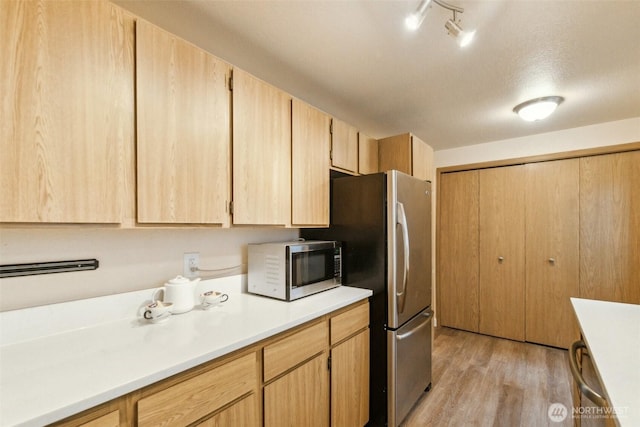 kitchen with light brown cabinetry, light countertops, track lighting, light wood-style floors, and stainless steel appliances