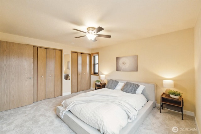 bedroom with carpet floors, a ceiling fan, multiple closets, and baseboards